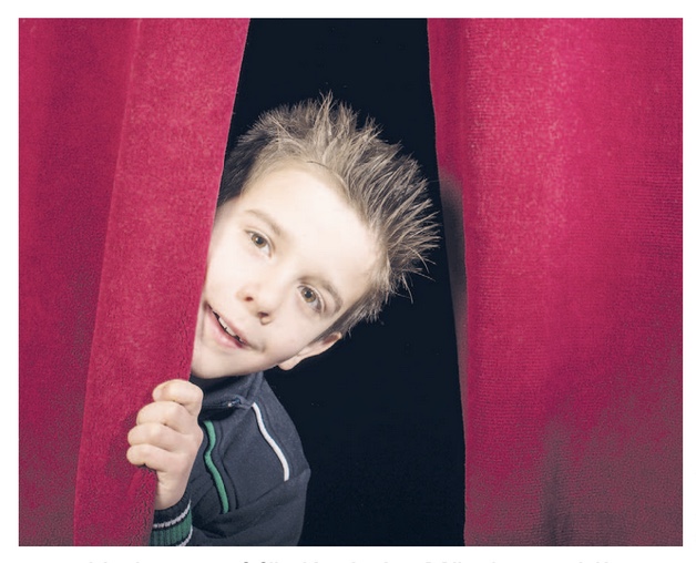 Ein Junge schaut hinter einem Theatervorhang hervor. Das Bild stammt aus einem Schultheaterstück mit dem Titel "Kevin allein im Wald."