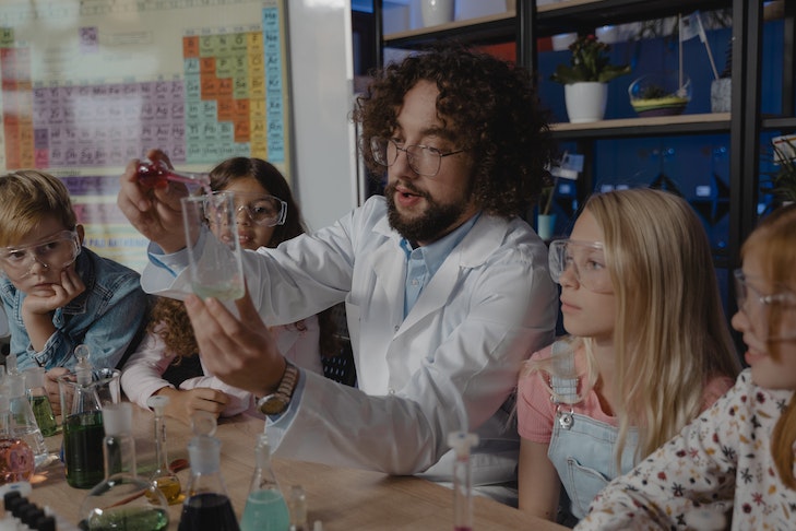 Ein Referendar erklärt seinen SchülerIinnen ein Experiment im Chemieunterricht.
