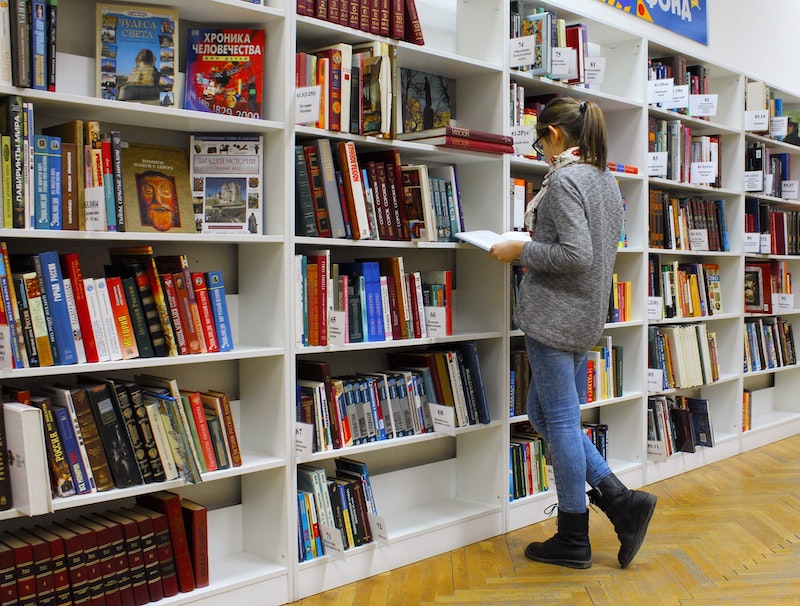 Ein Mädchen steht vor einem Regal voller Bücher und liest